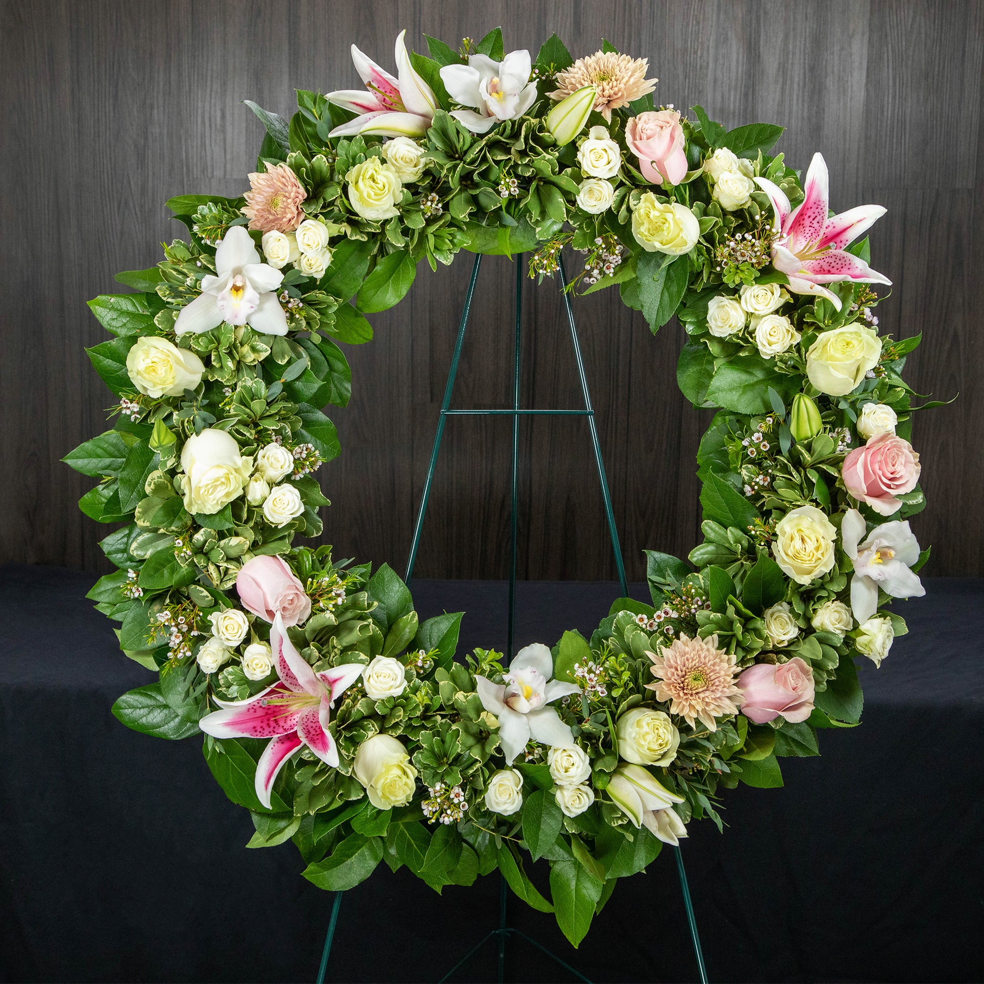 a 22 inch funeral wreath with mostly white flowers and pops of soft pink and peach