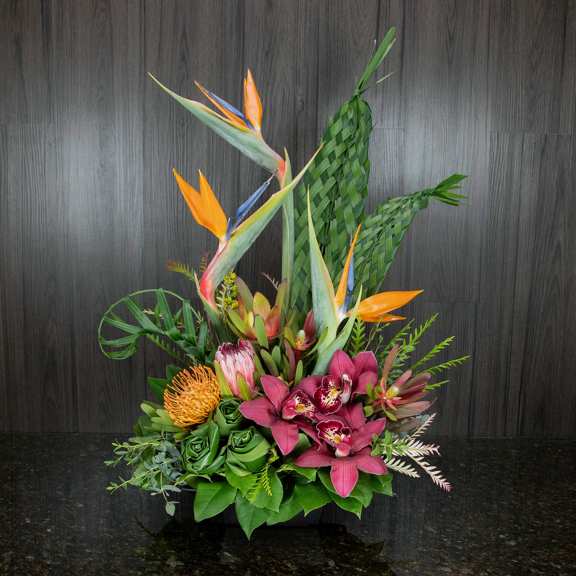 a tropical flower arrangement with three tall birds of paradise and a mix of tropical flowers