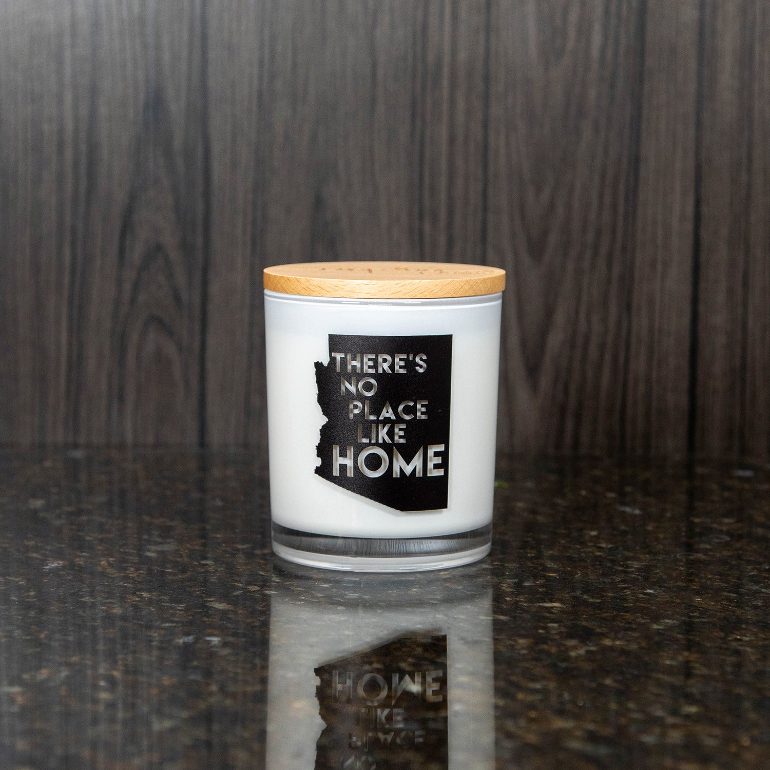 a white candle with a print of the shape of Arizona was "there's no place like home" written in it
